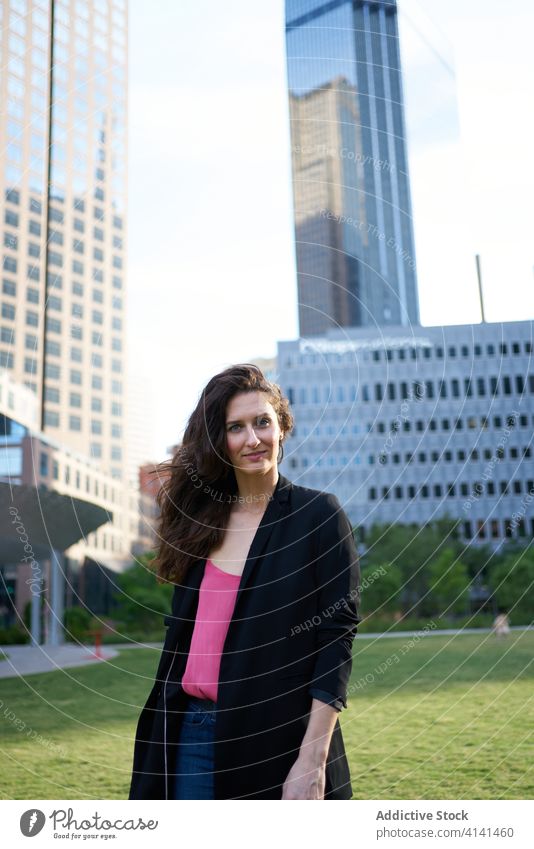Determined smiling businesswoman against skyscrapers in downtown determine professional confident city thoughtful entrepreneur high rise elegant female urban