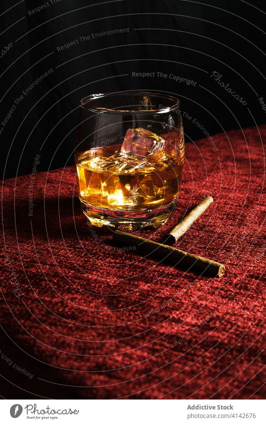 Close-up of one glass of whiskey on a table alcohol ice scotch whisky liquor background cold single brandy drink liquid reflection cube yellow isolated brown