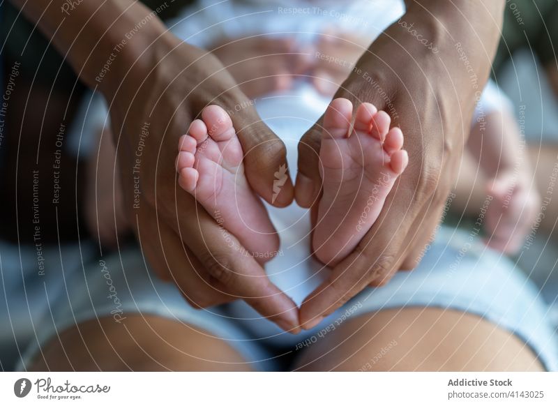Crop woman with feet of infant baby tiny mother newborn tender parent family heart ethnic shape love small little together care child affection adorable
