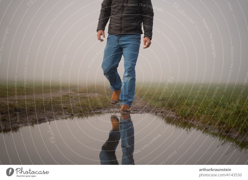 Young man walking in the fog in nature towards a puddle of water on one's own Going Man Nature Fog outdoor Puddle stroll reflection Hiking Water Meadow