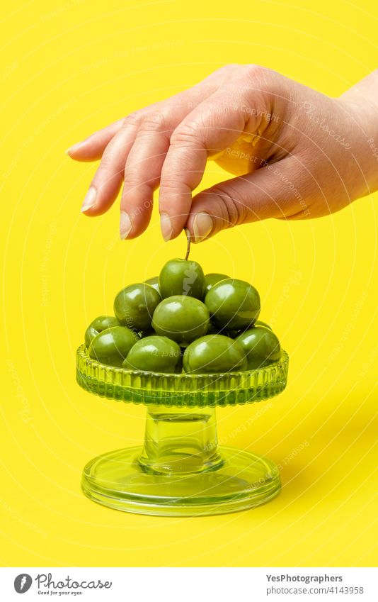 Woman hand taking a green olive. Eating fresh organic olives Olea europaea appetizer background close-up color colorful copy space cuisine cut out delicious