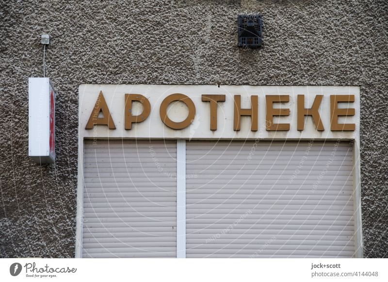 APOTHEKE in rural areas Pharmacy lettering house wall Gray Characters Entrance Pharmaceutics Signs and labeling Lightbox Roller shutter Weathered extractor hood