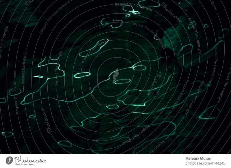Waves of light reflections on dark background, rocky. Abstract curves of fluorescent light. Dark background with organic, liquid light lines. abstract