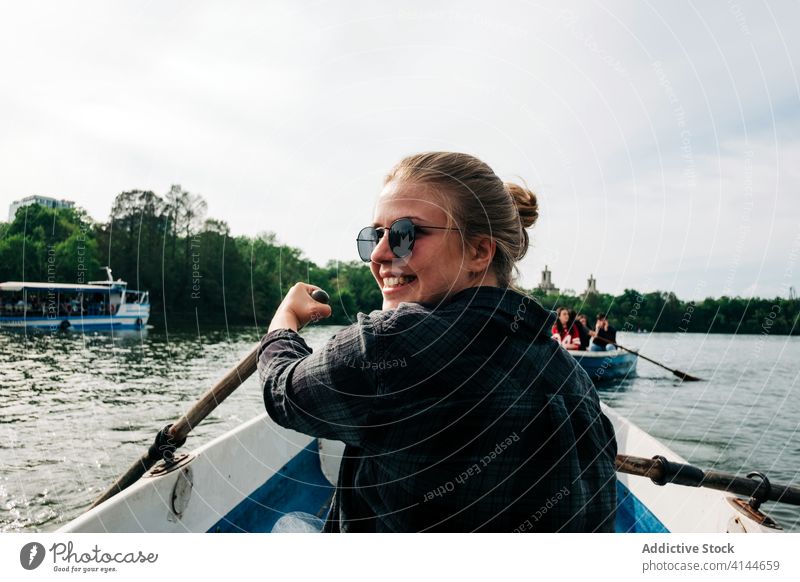 Cheerful woman rowing on boat on lake surface positive cheerful sculling oar smile nature activity peaceful calm relax summer happy leisure lifestyle female