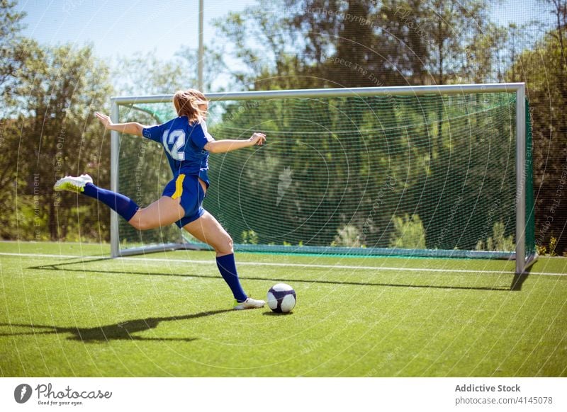 Anonymous sportswoman kicking ball into goal football field game professional training female uniform grass soccer activity athlete sportswear score competition