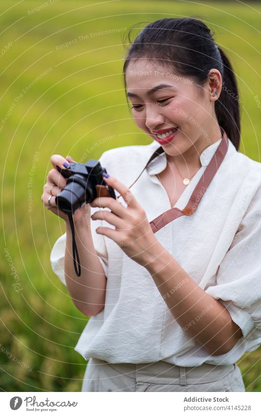 Smiling ethnic woman taking photo in field take photo vintage photo camera nature rice moment memory smile female asian summer photography photographer vacation