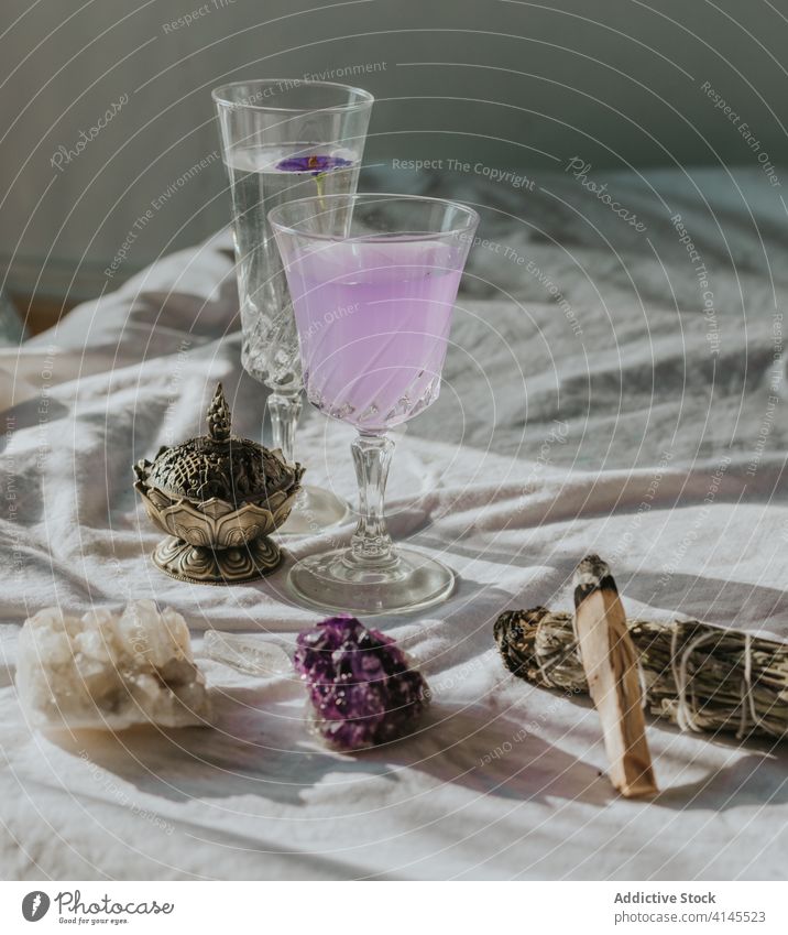 Natural minerals arranged with cocktails and aromatherapy equipment quartz amethyst natural glass burner tablecloth shadow composition beautiful spa white linen