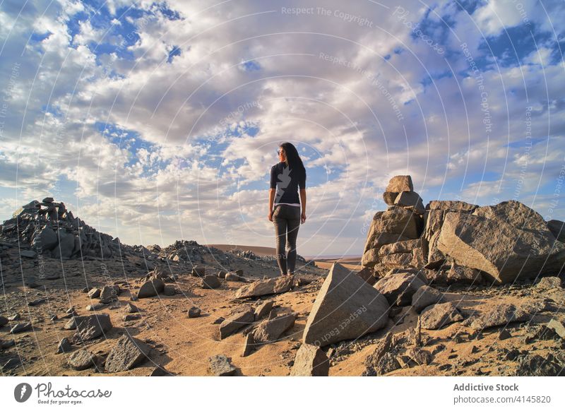 Unrecognizable tourist exploring picturesque desert with shapeless stones in daylight explore nature tourism spectacular idyllic sand bumpy scenery Asia woman