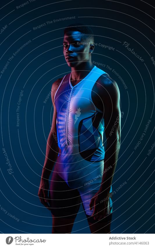 Strong ethnic sportsman looking at camera athlete confident serious concentrate brutal competitive determine neon challenge blue active physical young black