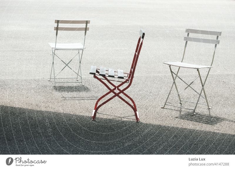 2x Snow White and 1x Rose Red: three folding chairs with their shadows are standing in the sun, two of them white and one red. Chair Folding chair Spring Bright
