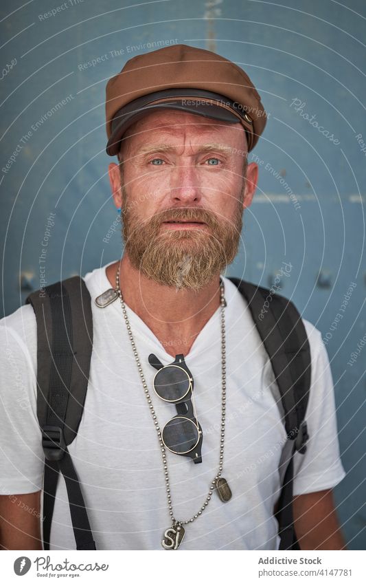 Hipster male traveler with backpack hipster man trendy style beard backpacker adult hiker portrait cap accessory modern confident serious tourism individuality