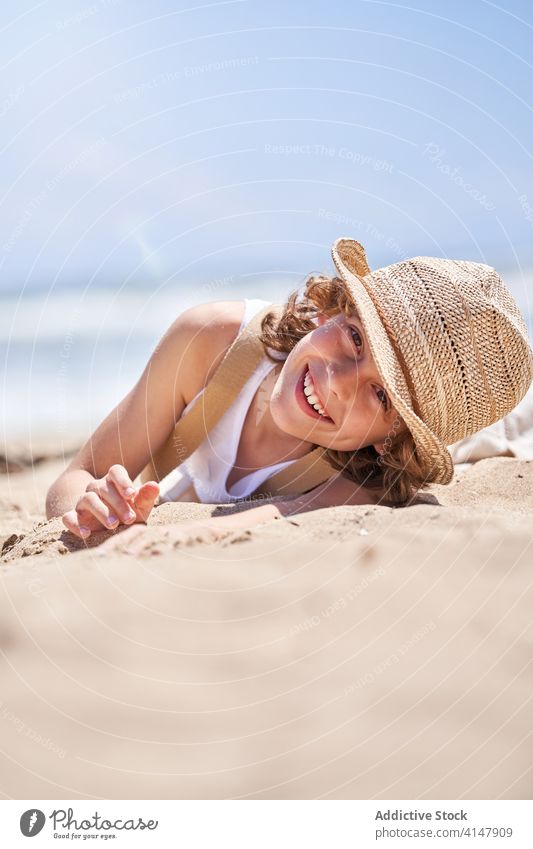 Smiling boy on sandy coat during summer holidays cute lying rest seashore beach barefoot resort carefree seaside vacation little coast kid child happy relax