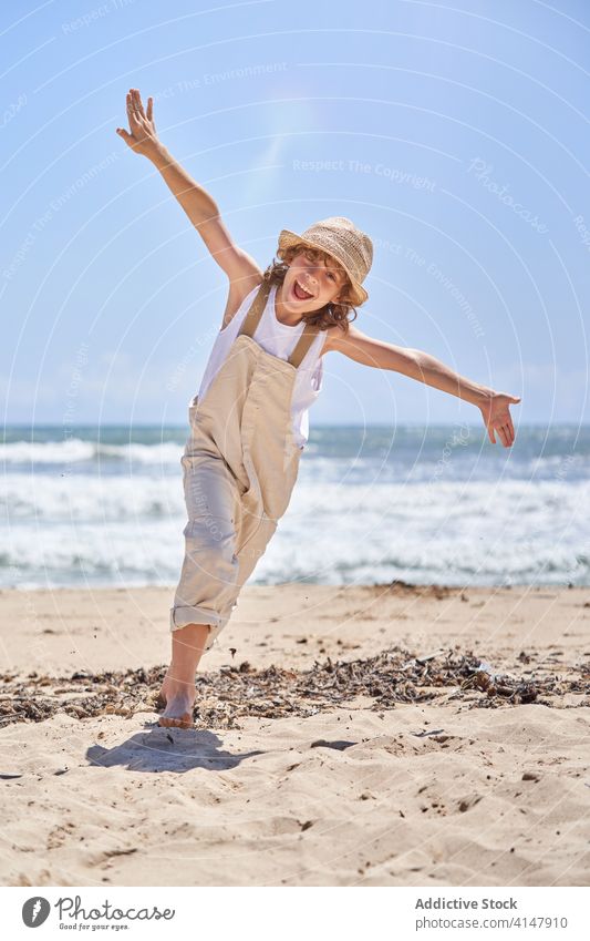 Happy boy running on sandy beach with arms outstretched having fun euphoria excitement child active scream seaside summertime vacation happy mouth opened