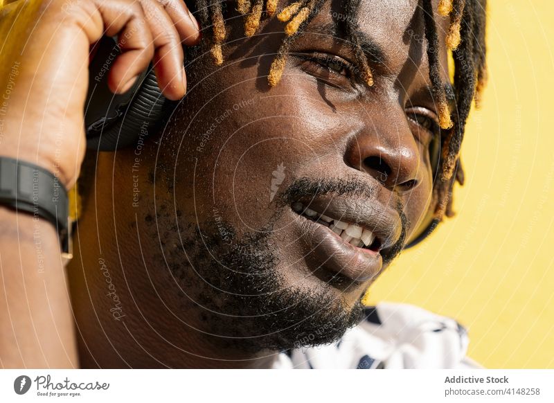closeup of black man listening and enjoying music person headphone african american portrait lifestyles young afro smiling guy audio handsome cool happiness