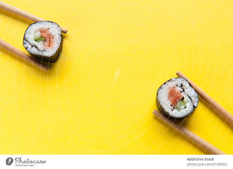 Appetizing rolls and chopsticks on yellow background sushi studio salmon rice delicious asian food tasty tradition meal table cuisine dish fresh gourmet seafood