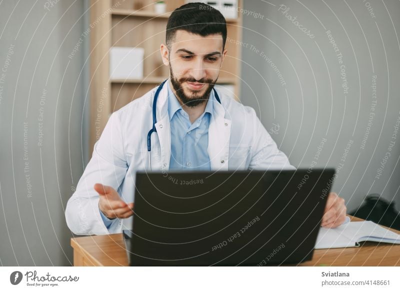 Young male doctor conducting online video consultation on laptop in his office patient health clinic stethoscope therapist online counseling diagnostics