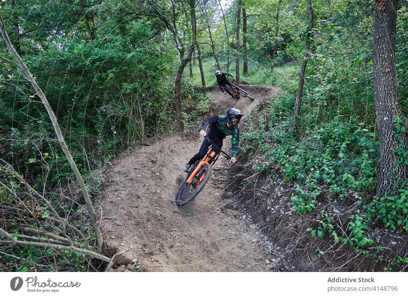Cyclist riding bicycle in forest downhill trick man extreme stunt ride cyclist risk helmet enduro perform professional woods woodland nature protect activity