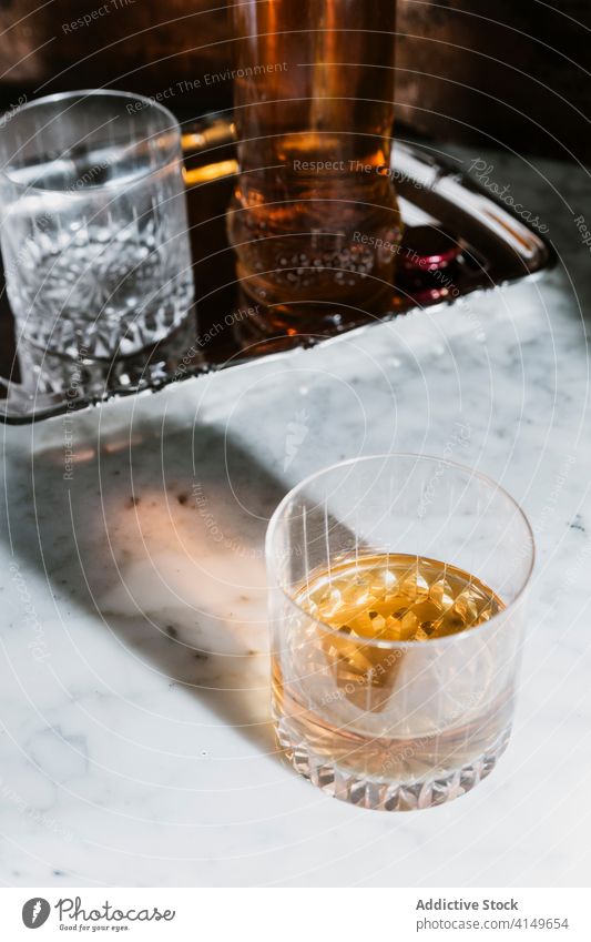 Glass of alcohol beverage on marble table whiskey bar glass drink bottle serve counter booze refreshment pub transparent modern style cold event celebrate