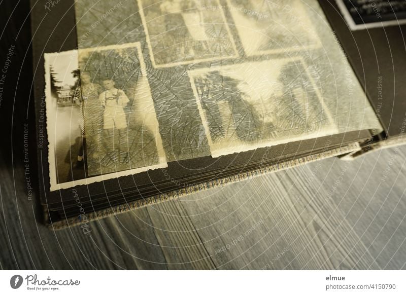 View into an old photo album with black and white photographs and parchment paper between the black pages / analog photography / dementia therapy Photo album