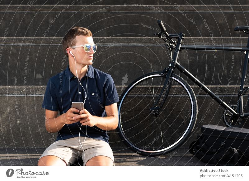 Man sitting on stairs on the smartphone bicycle bike blond business caucasian mobile phone communication copy space cycling cyclist entrepreneur freelance