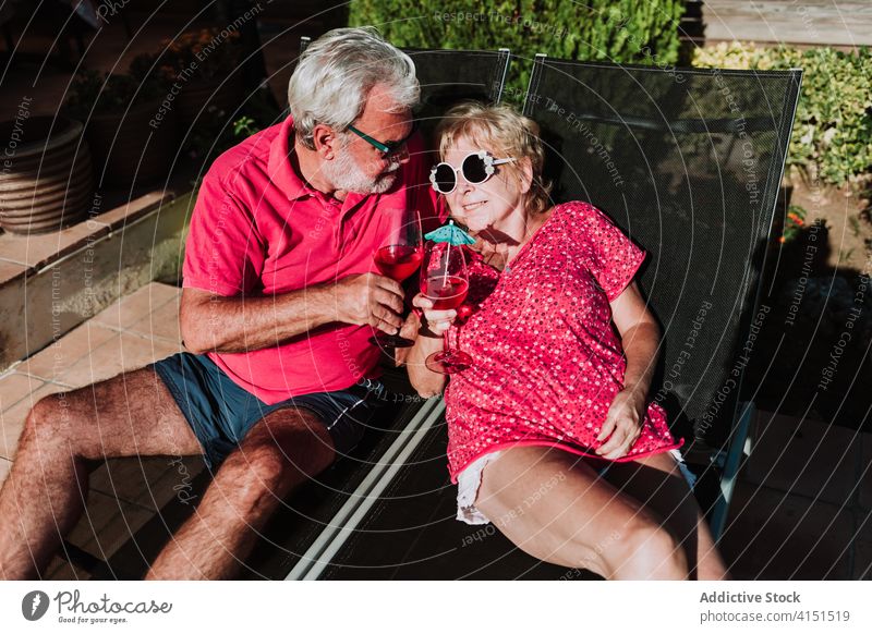 Content elderly couple on deck chairs summer vacation cocktail tropical senior relax together deckchair lying terrace beverage chill enjoy holiday drink