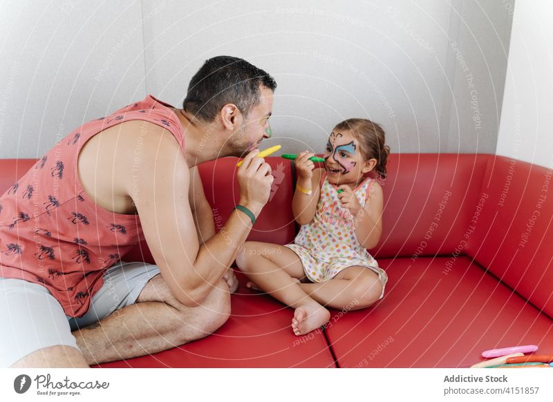 Cute child with father at home paint face having fun parent daughter together cute bonding calm painting girl adorable relax love sofa weekend kid rest couch