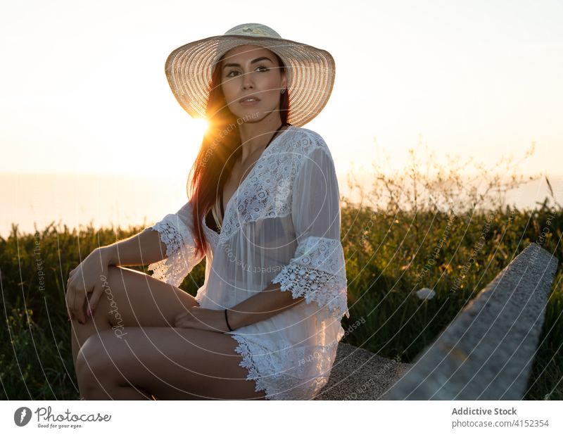Happy woman resting in nature sunset summer using happy relax evening sea seaside grass content young female style lifestyle lady vacation travel tourism
