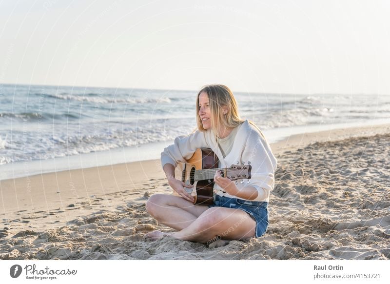 Young caucasian woman playing acoustic guitar on sandy beach.travel lifestyle, summer vacation background with copy space. Woman Guitar Playing Beach Summer