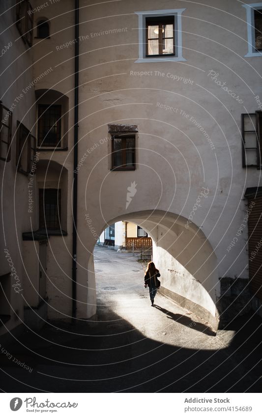 Woman walking through arch of old building archway woman architecture aged stone passage entrance female travel town wall tourism germany austria sightseeing