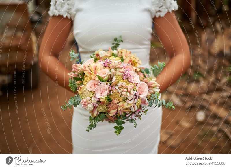 Crop bride with bunch of flowers on the street wedding bouquet elegant newlywed blossom female celebrate event romantic white dress marriage gown luxury bridal