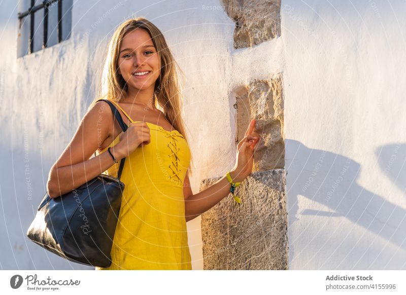 Content woman in dress near building city tourist summer sunlight vacation historic town sunny female wall stone travel street delight holiday enjoy smile happy