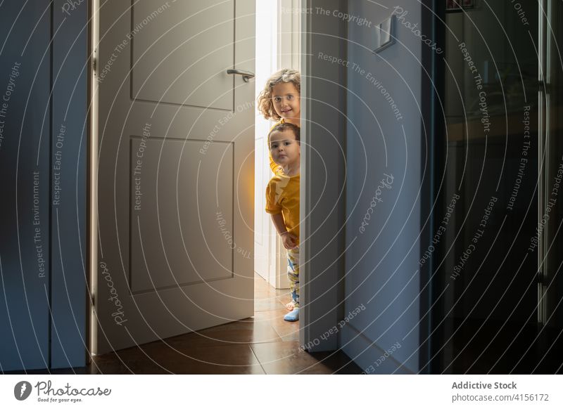 Cute siblings in doorway at home peep children playful brother sister having fun little apartment together cheerful modern cute adorable joy happy cozy smile
