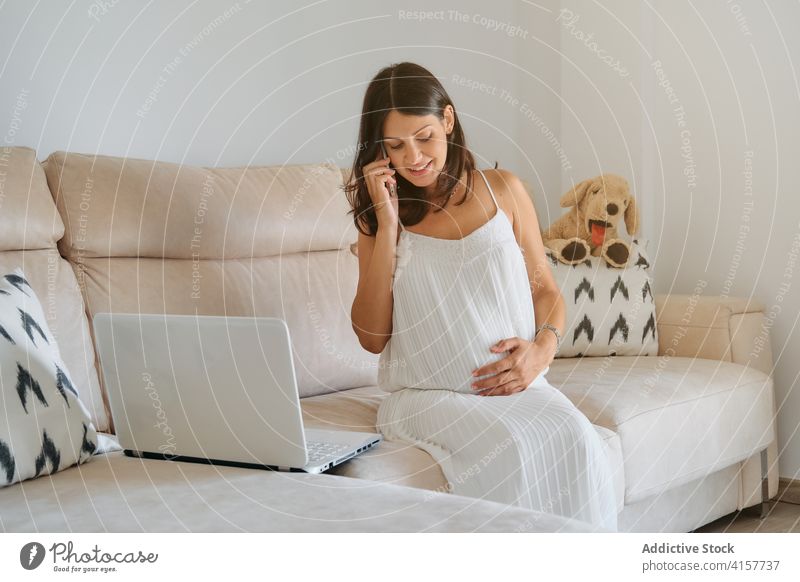Pregnant woman touching her belly while talking on the phone responsibility stomach motherhood birth bonding newborn planning symbolic fertility femininity