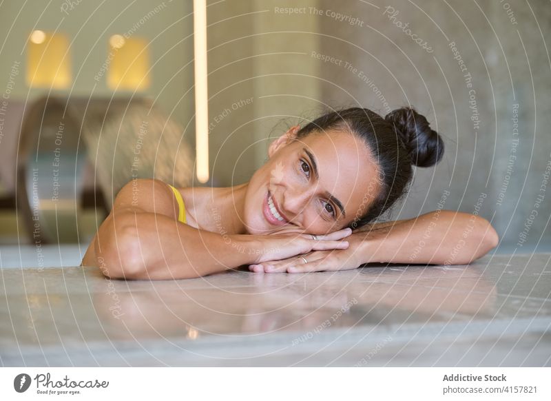 Cheerful woman enjoying spa procedure in pool relax hydrotherapy water wellness chill happy smile recreation rest young female resort vacation cheerful client