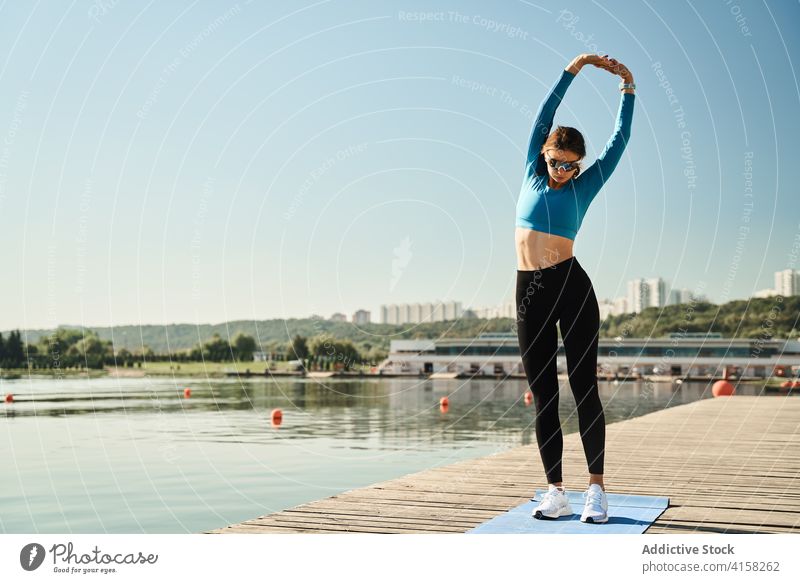 Sporty woman stretching body on riverside training fit slim workout fitness exercise embankment sporty bend active female warm up healthy shore flexible