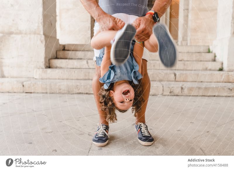 Positive man playing with cute girl on street father daughter toss having fun game fatherhood love city together weekend childhood parent bonding passage