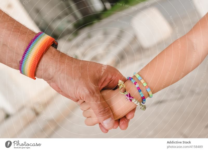 Crop homosexual father and child holding hands gay kid man fatherhood rainbow bracelet together little city weekend childhood love relationship bonding parent