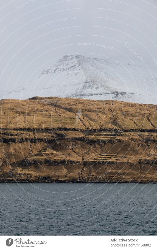 Rocky cliff near sea on Faroe Islands rock seascape winter snow season cold steep terrain faroe islands rocky scenery majestic coast shore water sky calm