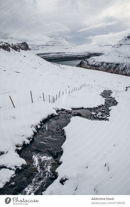 Cold brook in snowy countryside water winter cold overcast sky mountain nature landscape scenic cool flow ridge environment range creek Faroe island cloudy