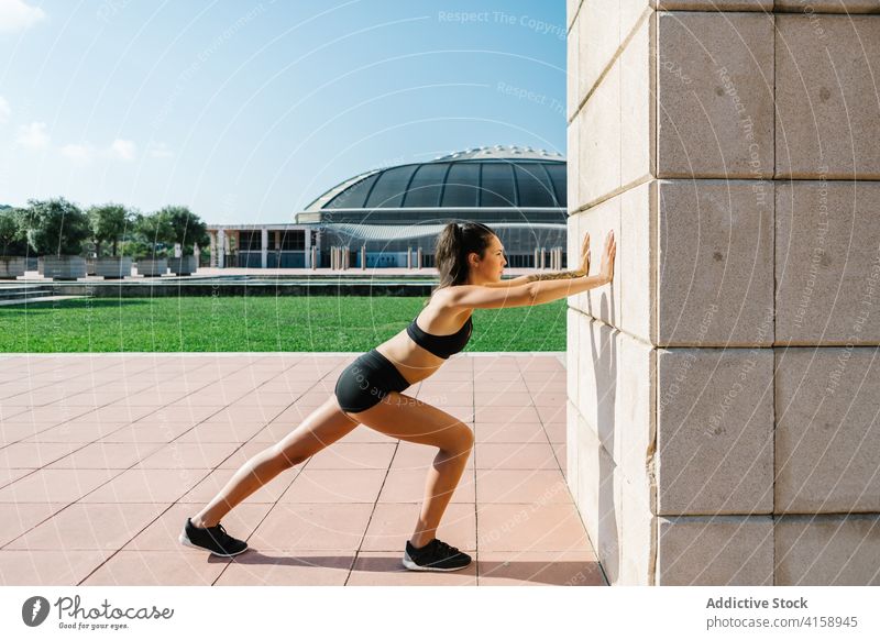 Sporty woman doing stretching exercise near wall training calf street urban workout athlete fit sportswoman female runner jogger muscle young slim fitness