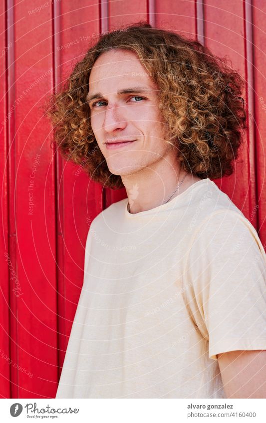 a stylish young man with curly hair and green eyes smiling and looking at the camera che attractive person male guy casual white handsome one isolated portrait
