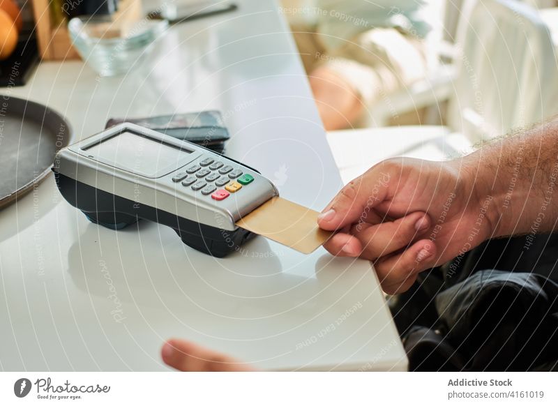 Crop man paying by plastic card in cafe credit card payment terminal contactless order customer purchase service money commerce finance nfc male casual online