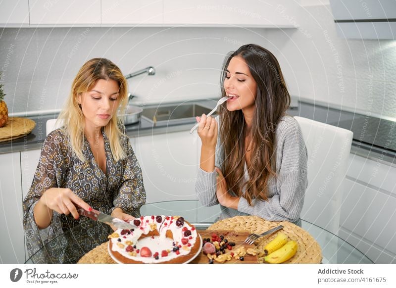 Happy women eating vegan dessert in kitchen healthy food cake enjoy pastry homemade diet berry young female sweet delectable tasty delicious girlfriend positive