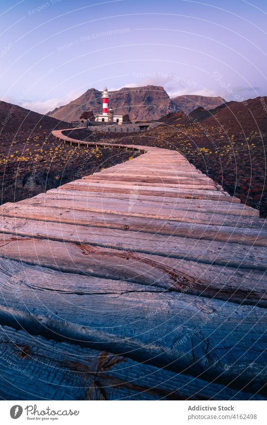 Lonely lighthouse on rocky coast in morning beacon mountain sea path road hill highland canary islands spain tenerife building construction pathway scenic