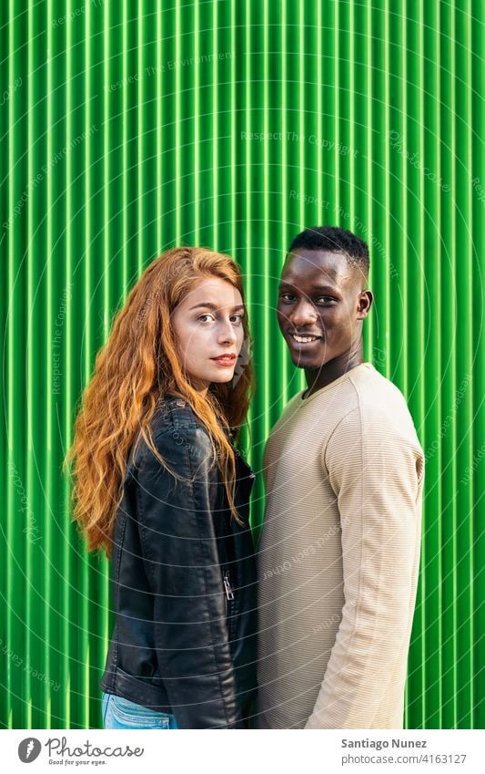 Multiethnic Couple Portrait green background portrait looking at camera smiling front view relationship multi-racial black man caucasian multi-cultural