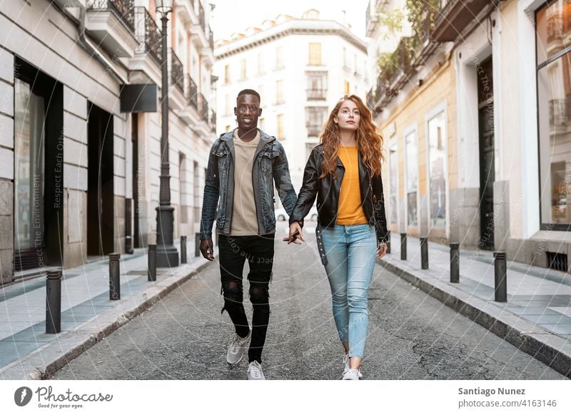 Lovely Couple Holding Hands walking holding hands front view street looking at front portrait relationship multi-racial black man caucasian multi-cultural