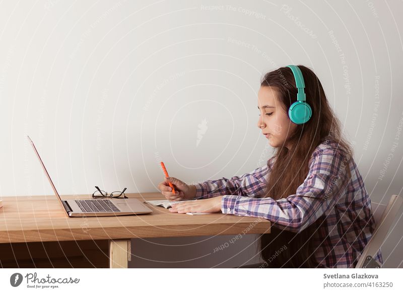 Distance learning at home.Student with a laptop listening to a webinar online with headphones. Elearning concept distance education girl female child childhood