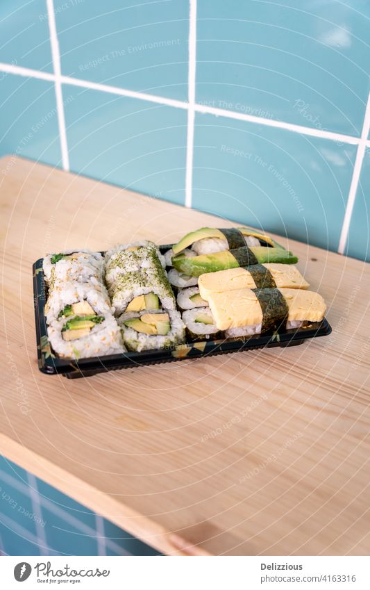Fresh vegetarian sushi take away on wooden surface and blue tile background food no people nobody healthy healthy diet healthy eating no fish tiles