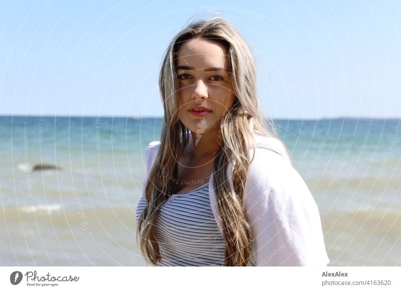 Beautiful blonde girl stands on the beach of the Baltic Sea and looks into the camera Girl Smiling joyfully Landscape by Blonde Joy Exterior shot Face