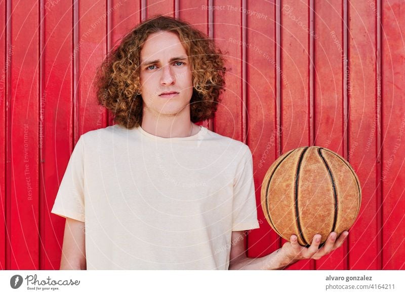 a young man with curly hair and green eyes looking at the camera with a basketball ball in his hand che person sport athletic male game player competitive
